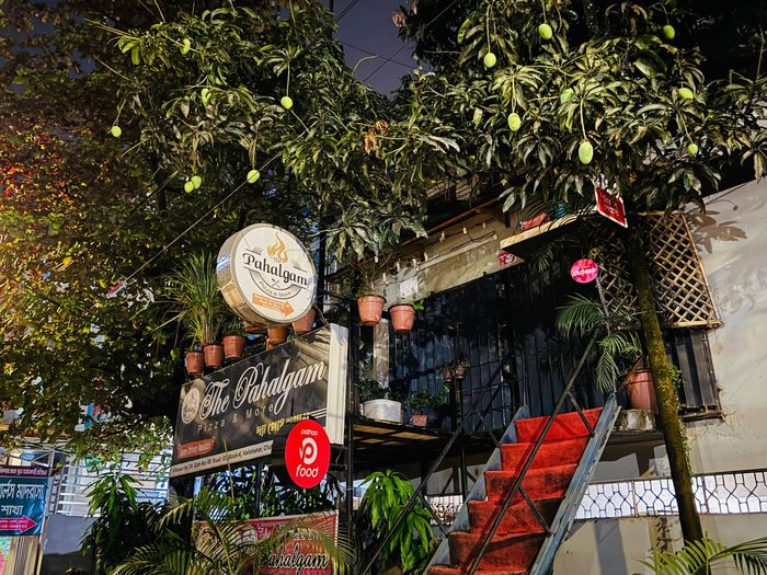 The Pahalgam signage lit up under the mango trees at night
